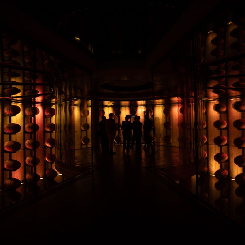 A group of people gathered in a darkened room illuminated by deep reds and ambers