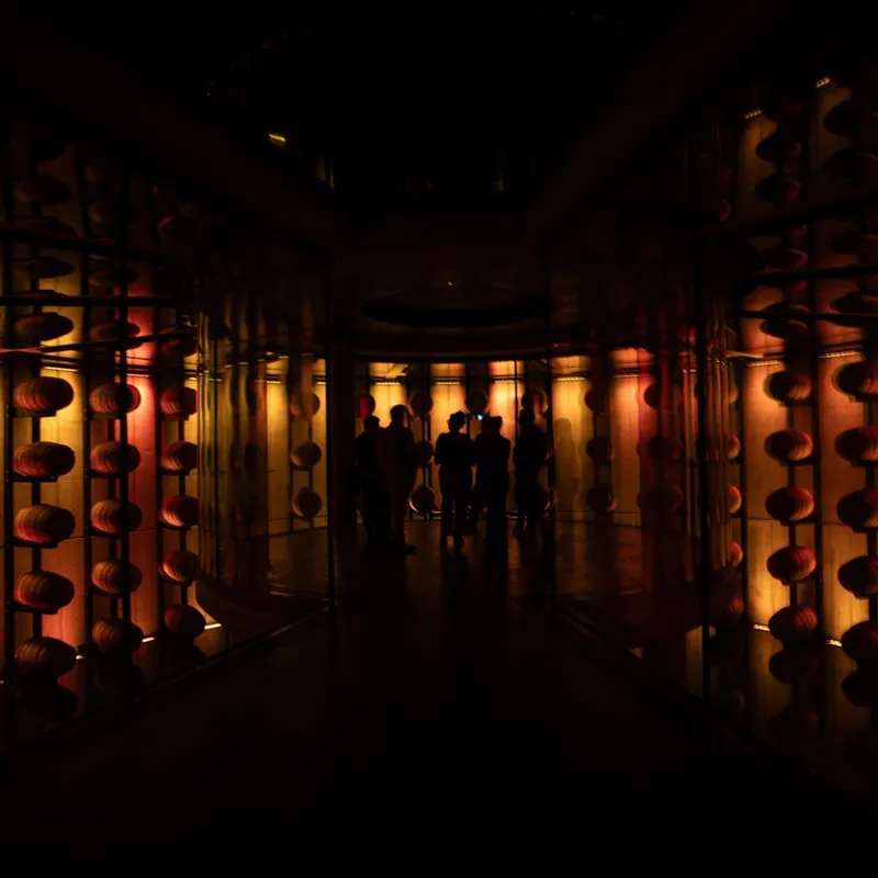 A group of people gathered in a darkened room illuminated by deep reds and ambers